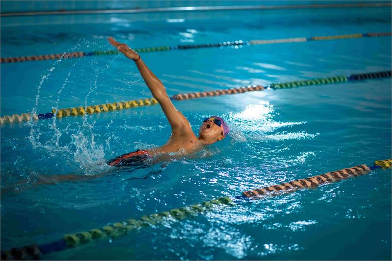 At the best private school in Gurgaon, a swimmer enjoys a peaceful night swim in a well-lit pool.