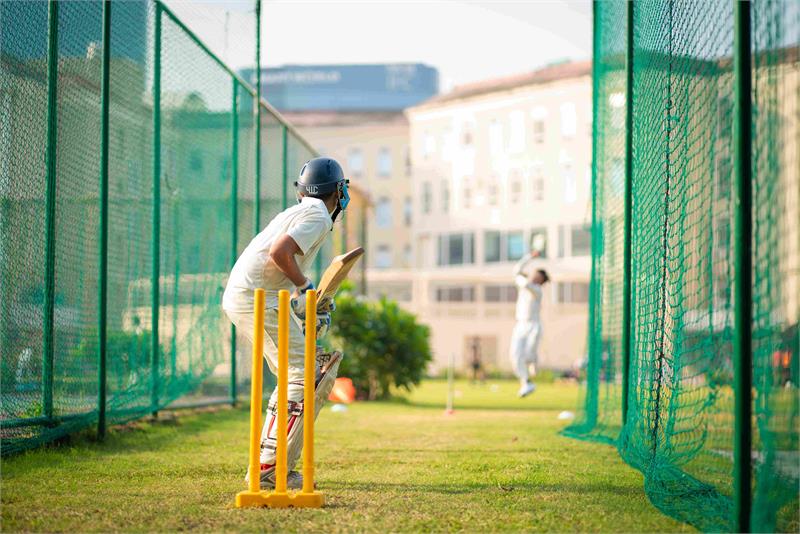 At the best CBSE school in Gurgaon, a man shows great sportsmanship playing cricket on a sunny day.