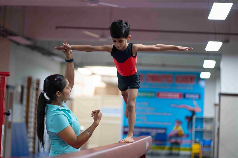 A girl at the best cbse school in Gurgaon excels in gymnastics, gracefully performing on the beam